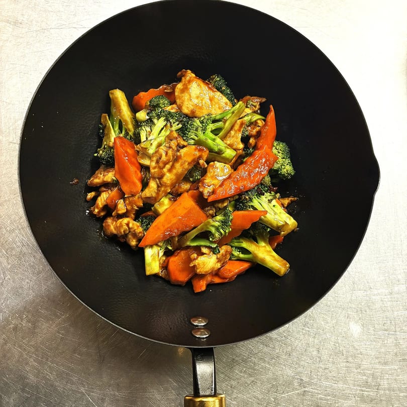 Chicken and broccoli stir-fry with carrots in a black wok from Orient Express Webb City.